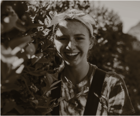 девушка улыбающаяся на фоне кустов винограда
